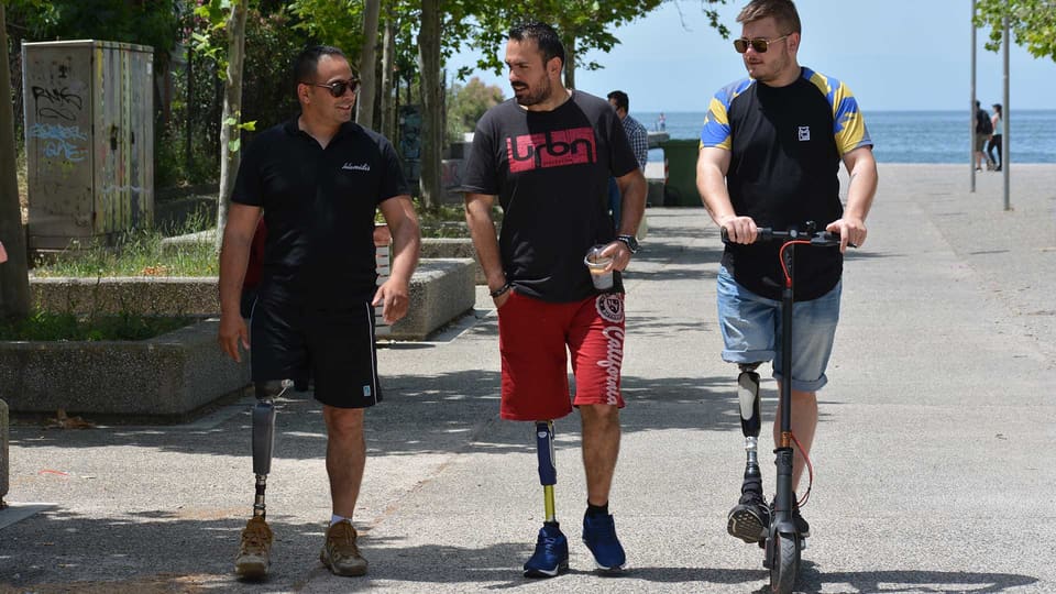 Men with prosthetic legs walking along the Thessaloniki seafront – above-knee and below-knee prostheses