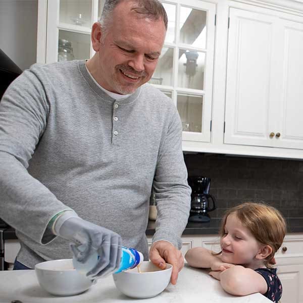 User with an Össur i-Limb Quantum prosthetic hand holding his child