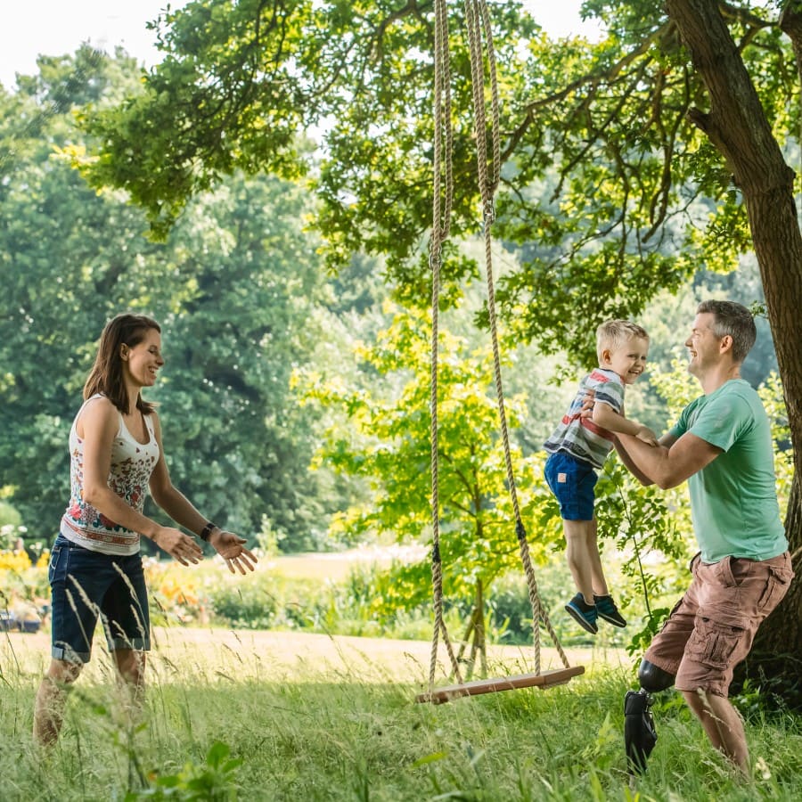 A father with a prosthetic leg playing with his child in a park