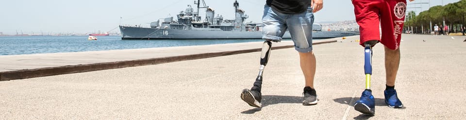 Two lower-limb prosthesis users walking along the Thessaloniki seafront