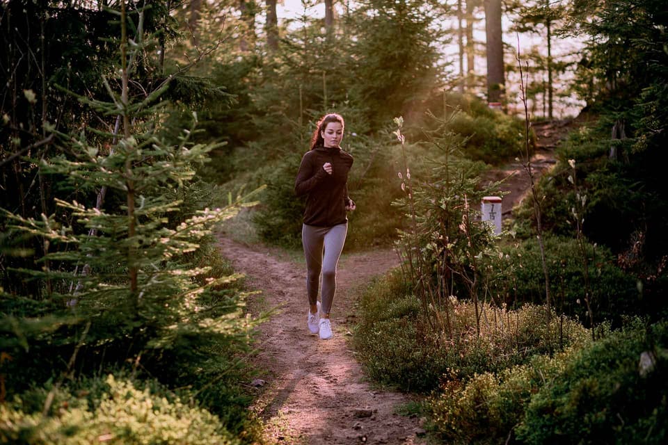 Woman running on a forest trail, illustrating the use of 8Sole insoles for running